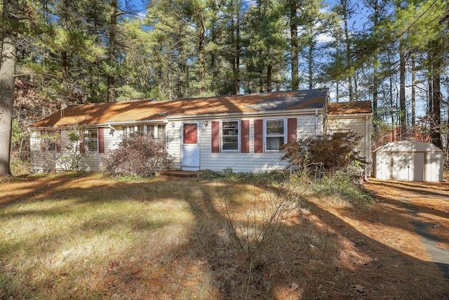 ranch-style home featuring a front lawn and a shed