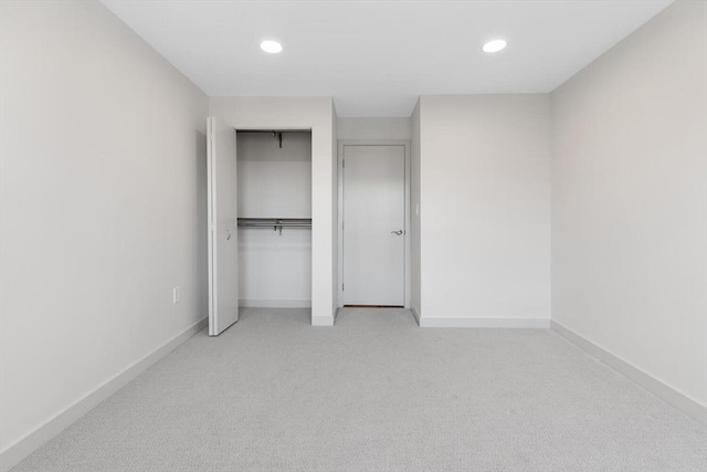 unfurnished bedroom with light carpet and a closet