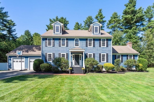 colonial home with a front lawn, an attached garage, and aphalt driveway