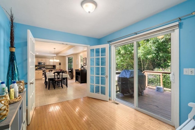 doorway to outside featuring light wood-style floors, visible vents, a chandelier, and french doors