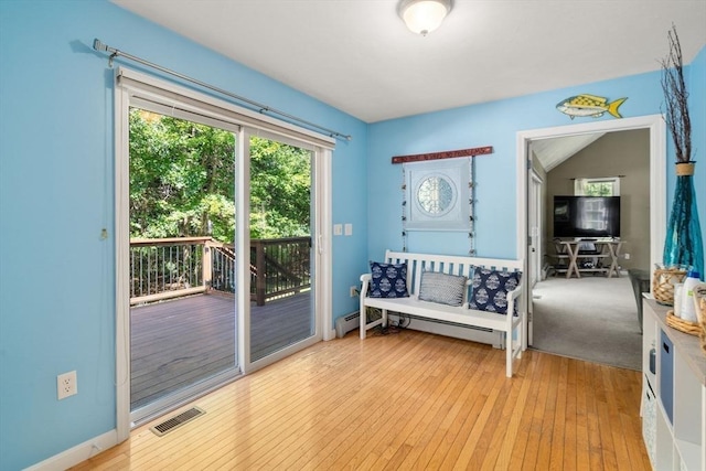 doorway to outside featuring a baseboard heating unit, visible vents, and light wood finished floors