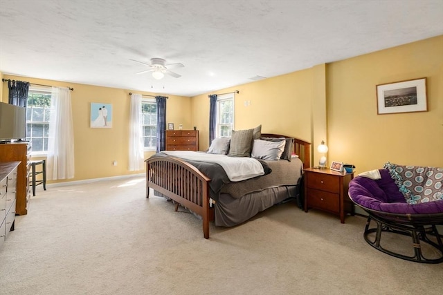 bedroom featuring light carpet, ceiling fan, and baseboards