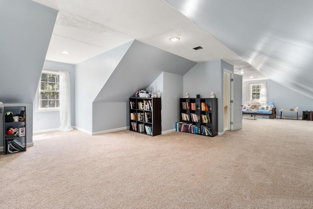 additional living space featuring lofted ceiling, visible vents, baseboards, and carpet flooring