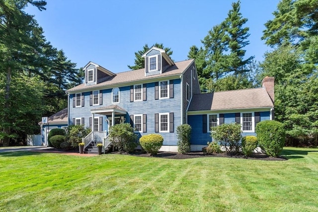 colonial house featuring a chimney and a front lawn