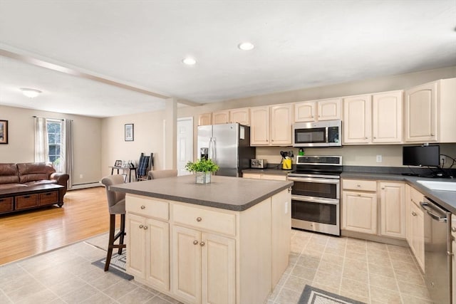 kitchen featuring open floor plan, stainless steel appliances, a breakfast bar, and dark countertops