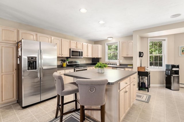 kitchen with dark countertops, a kitchen bar, a kitchen island, and stainless steel appliances