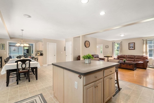 kitchen with a notable chandelier, a kitchen island, open floor plan, dark countertops, and pendant lighting