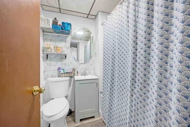 bathroom featuring a paneled ceiling, curtained shower, wood finished floors, vanity, and toilet