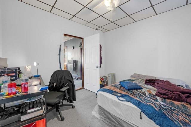 bedroom with radiator heating unit, carpet floors, a ceiling fan, and a drop ceiling