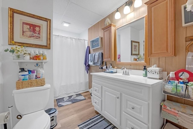 bathroom with vanity, wood finished floors, toilet, a paneled ceiling, and a shower with curtain
