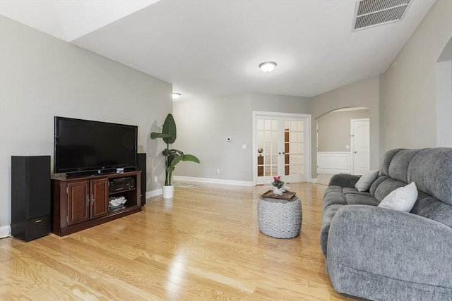 living room with french doors, visible vents, arched walkways, baseboards, and light wood-style flooring
