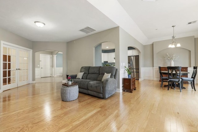 living area featuring visible vents, arched walkways, light wood-style floors, and french doors