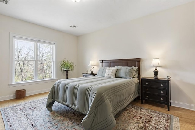bedroom featuring baseboards, visible vents, and wood finished floors