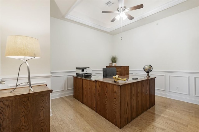 office space with visible vents, wainscoting, a decorative wall, light wood-style floors, and ceiling fan