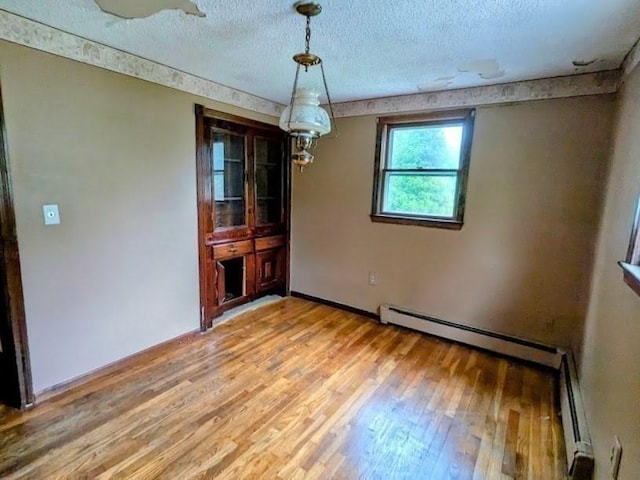 14 Reagan Rd, Townsend, MA 01469 - unfurnished dining area featuring light wood-style flooring, a textured ceiling, baseboard heating, baseboards, and a baseboard radiator