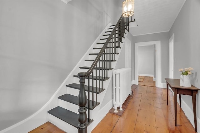 stairs featuring a chandelier, baseboards, radiator heating unit, and hardwood / wood-style flooring