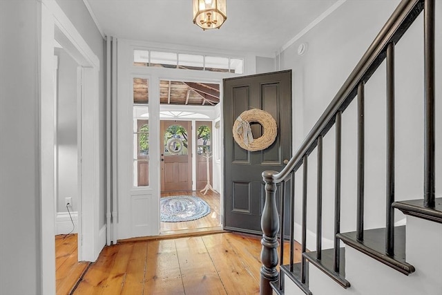 entryway featuring ornamental molding, light wood-type flooring, and stairway