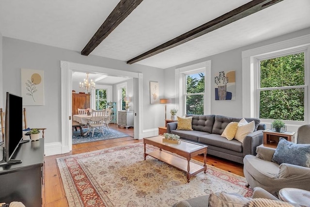 living room with baseboards, light wood-style flooring, a chandelier, and beam ceiling