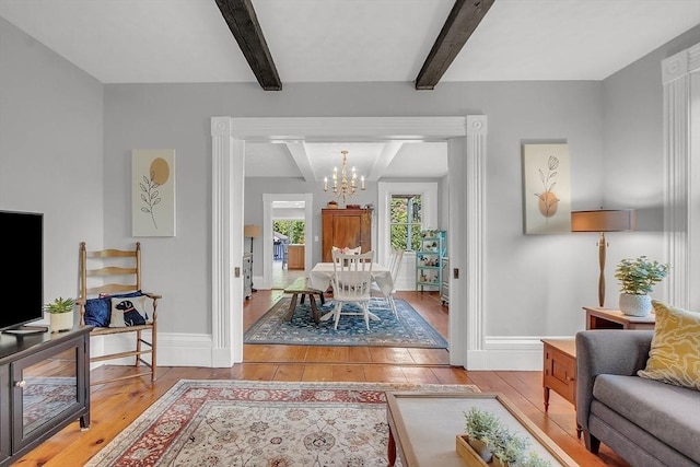 living area with light wood-type flooring, baseboards, a chandelier, and beam ceiling