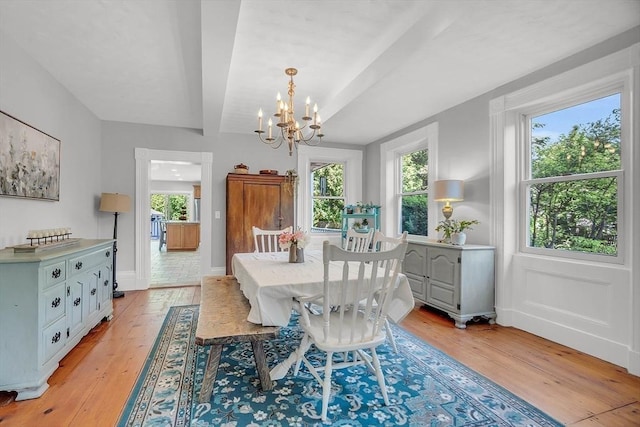 dining area featuring baseboards, beamed ceiling, light wood-style flooring, and a notable chandelier