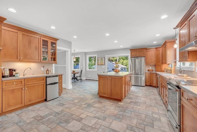 kitchen with a sink, stainless steel appliances, light countertops, and a center island