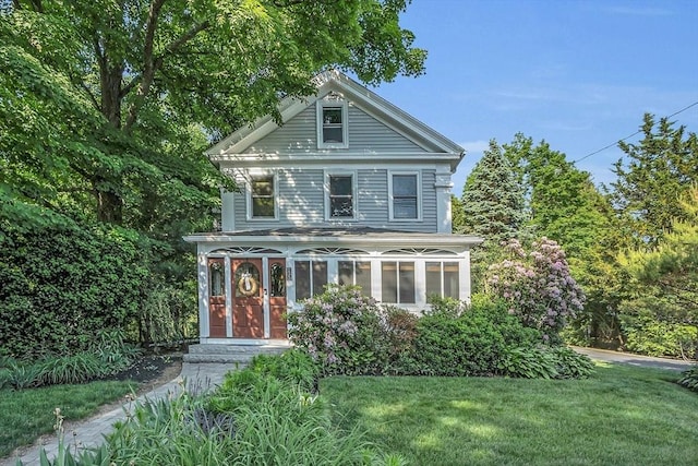 view of front of house featuring a sunroom and a front lawn