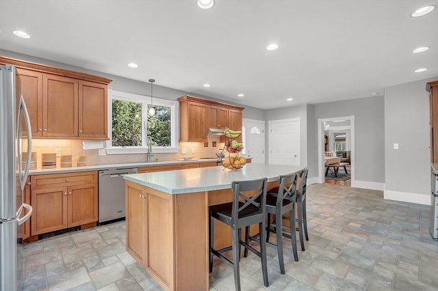 kitchen with baseboards, stone finish flooring, appliances with stainless steel finishes, and a center island