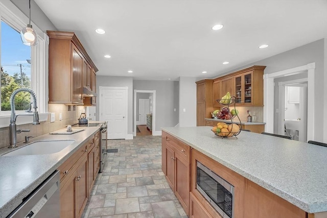 kitchen featuring brown cabinets, decorative backsplash, stainless steel appliances, and a sink