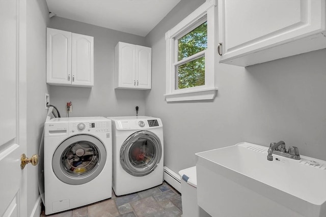 clothes washing area featuring cabinet space, stone finish flooring, washer and dryer, a baseboard heating unit, and a sink