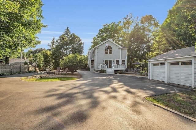 colonial house featuring fence, a porch, and an outbuilding