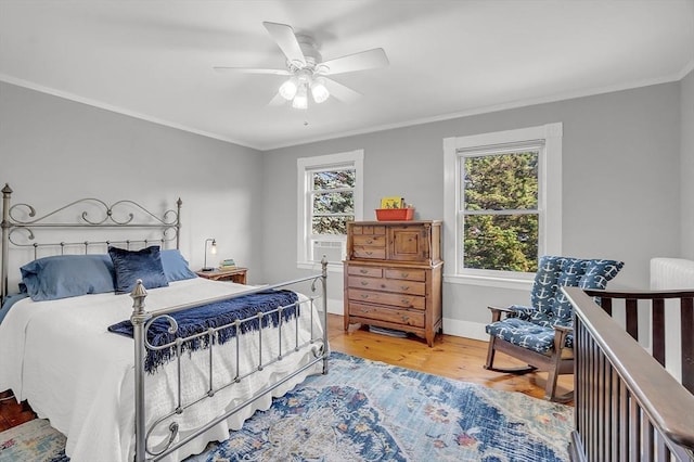 bedroom with light wood-style floors, baseboards, ornamental molding, and ceiling fan