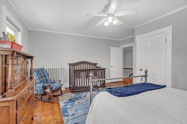 bedroom with radiator, crown molding, a ceiling fan, and wood finished floors