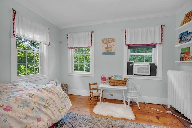 bedroom featuring baseboards, radiator heating unit, ornamental molding, and wood finished floors