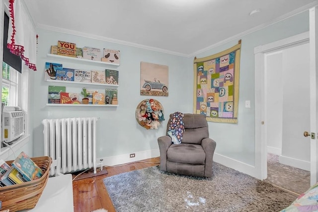 sitting room with radiator heating unit, ornamental molding, baseboards, and wood finished floors