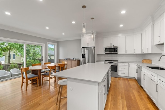 2 Rockwood Ter Unit 2, Newton, MA 02466 - kitchen featuring appliances with stainless steel finishes, a sink, a center island, ornamental molding, and light countertops