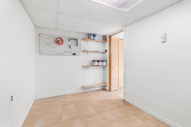 unfurnished room featuring a drop ceiling and baseboards