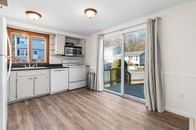 kitchen with a sink, light wood-type flooring, white appliances, and dark countertops