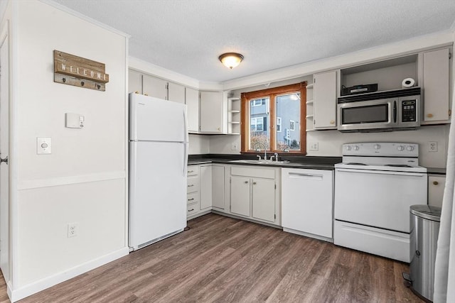 kitchen with open shelves, a sink, dark countertops, white appliances, and dark wood-style flooring