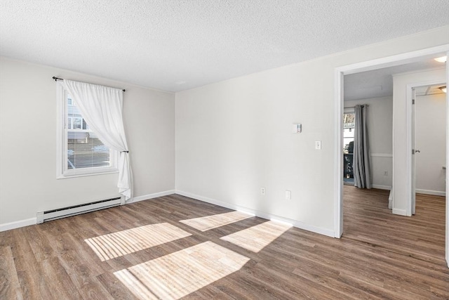 spare room with baseboard heating, a healthy amount of sunlight, and wood finished floors