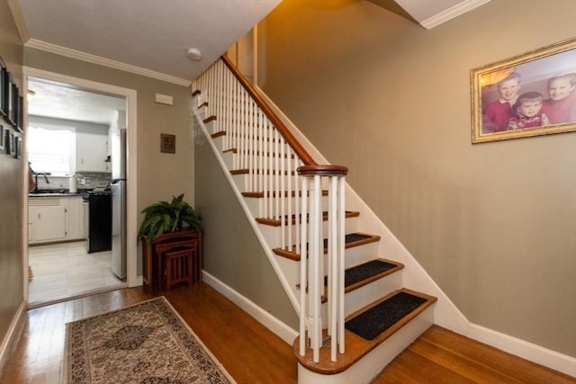 stairs featuring crown molding, hardwood / wood-style floors, and sink