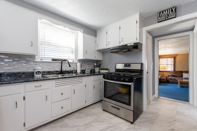 kitchen featuring decorative backsplash, a textured ceiling, stainless steel range with gas cooktop, sink, and white cabinetry