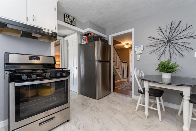 kitchen with appliances with stainless steel finishes, a textured ceiling, white cabinetry, and dark stone countertops