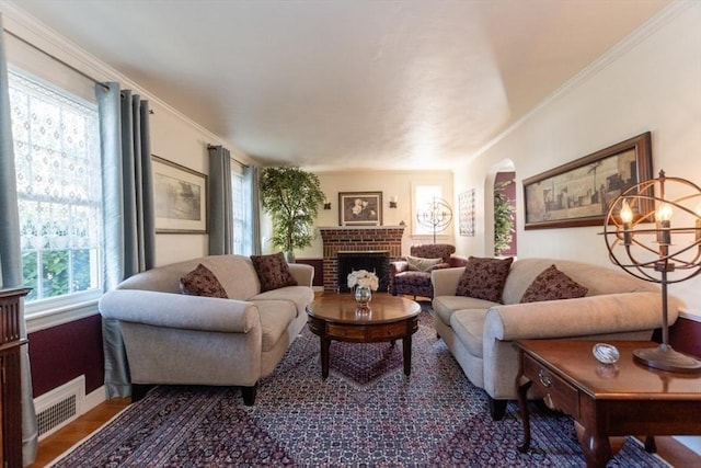 living room with hardwood / wood-style floors, a notable chandelier, crown molding, and a fireplace