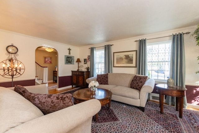 living room with a chandelier, crown molding, and a healthy amount of sunlight