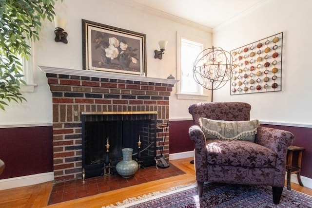 living area with a fireplace, hardwood / wood-style flooring, a chandelier, and crown molding