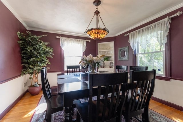 dining room featuring light wood-type flooring and crown molding