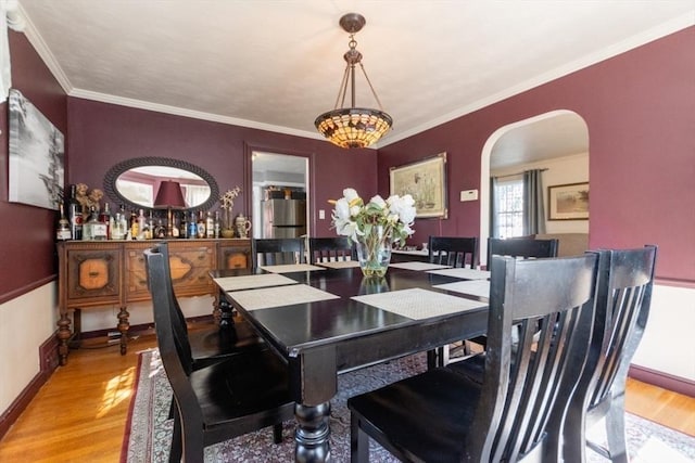 dining space with light wood-type flooring and ornamental molding