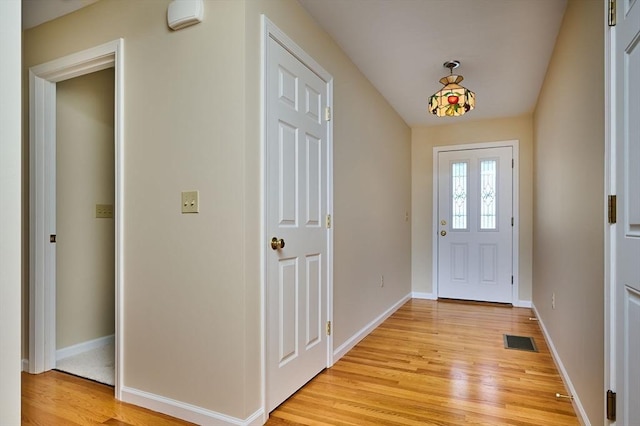 foyer entrance with visible vents, light wood-style flooring, and baseboards