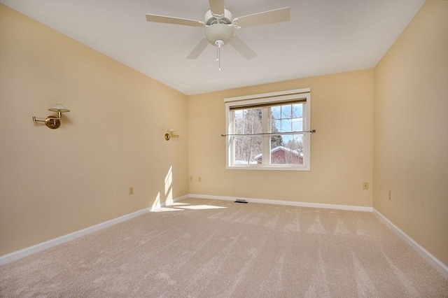 spare room featuring baseboards, light carpet, and a ceiling fan