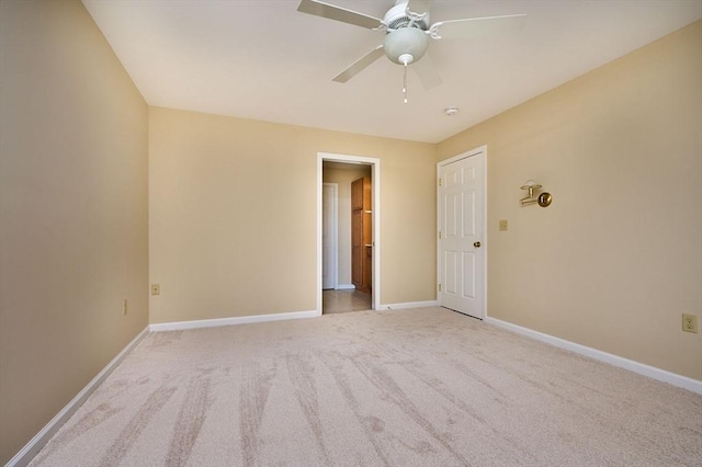 unfurnished room with a ceiling fan, light colored carpet, and baseboards